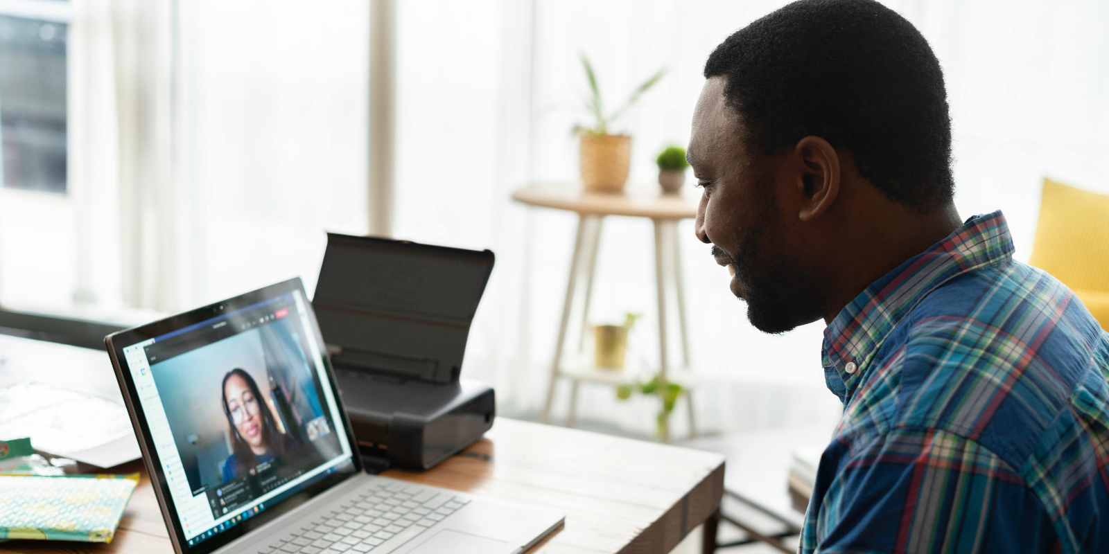Man sitting a a table looking down at his laptop watching a seminar